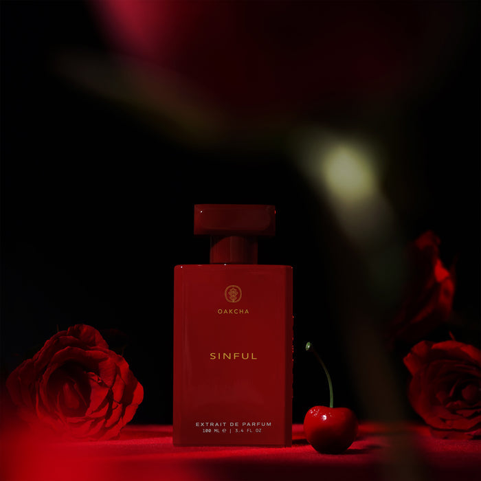Front view of Sinful 100 mL perfume bottle showing glossy red rectangular bottle and cap with cherry and roses on dark