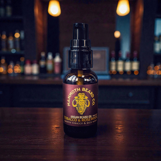 Mammoth Beard Co. Tobacco & Rosewood Argan Beard Oil in 30ml amber glass pump bottle on wood bar top, featuring smooth tobacco and rich rosewood essential oil blend for conditioning and softening beards.
