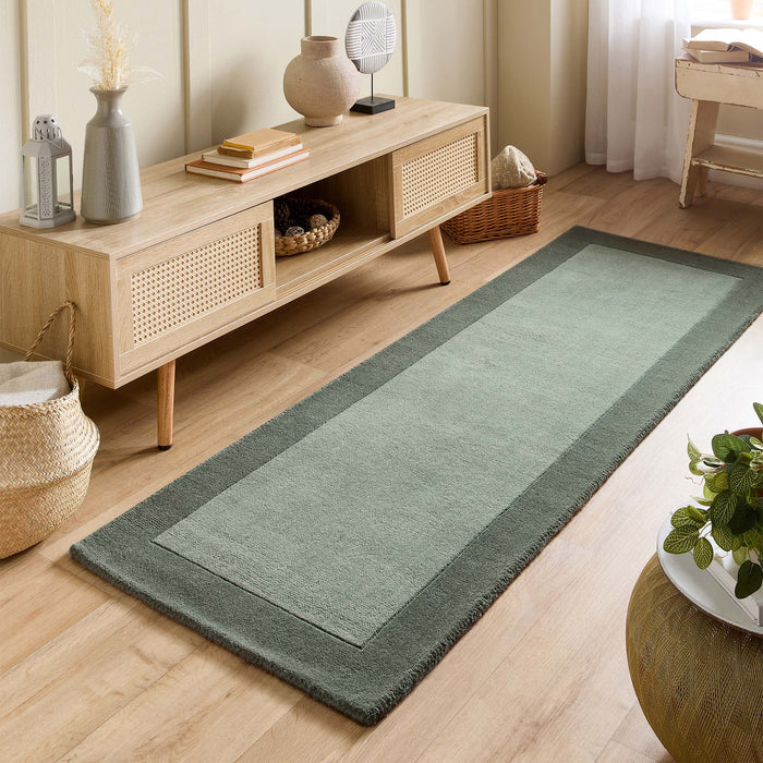 Borders Sage Green 100% wool runner with a two-tone border design, styled in a small room.