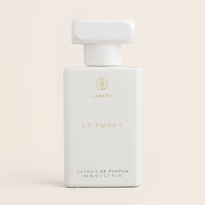 Front view of Le Funky perfume bottle showcasing a minimalist white rectangular bottle with gold lettering against a soft beige background