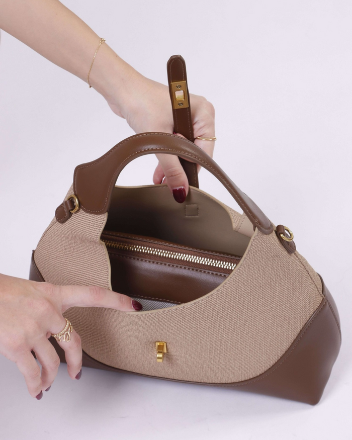 Two-tone handbag with top zip opening, open view showing interior access and strap