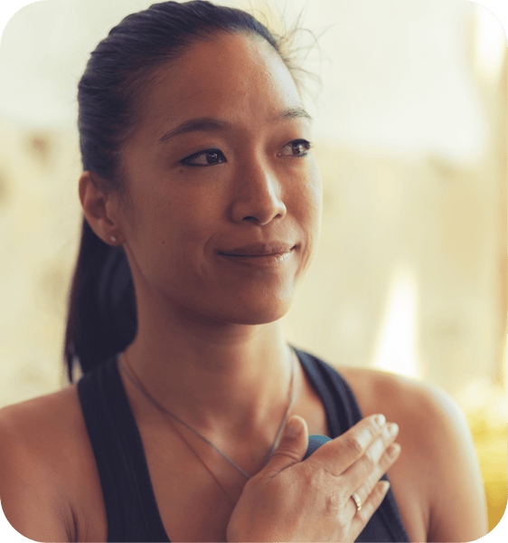 Woman holding a wellness device to her chest with a calm expression, promoting mindfulness and self-care with the RAD All In Kit | RAD.